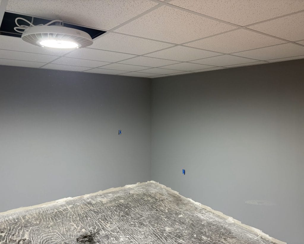 Drywall finished office with grid ceiling installed. Walls painted gray.